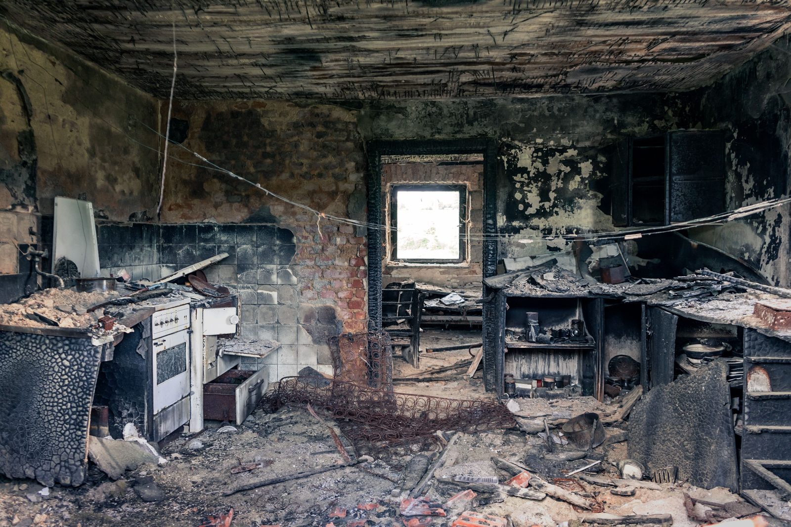 Burned-out kitchen after a stove fire, soot on every wall and the ceiling charred