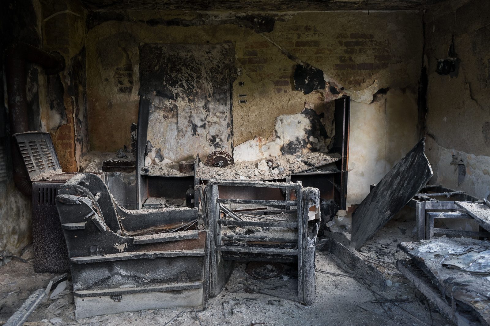 Burned living room with charred furniture and soot-blackened walls