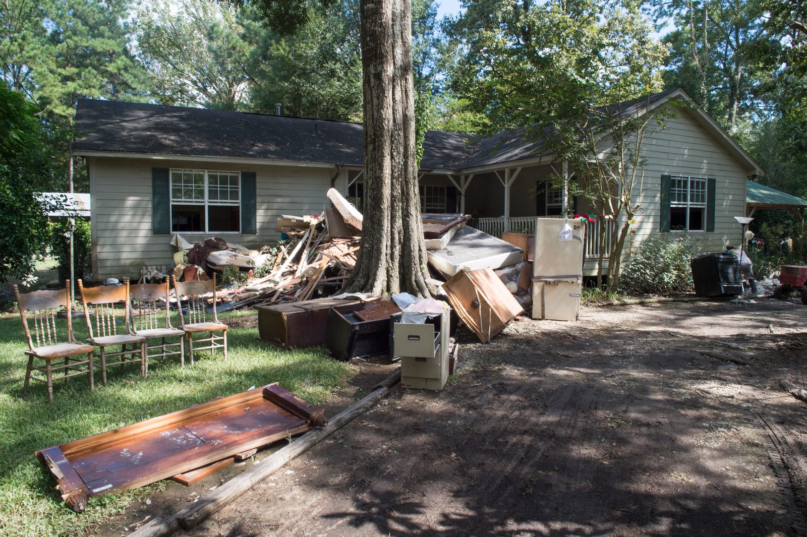 Soaked furniture, carpet and drywall stacked on the lawn outside a flooded house